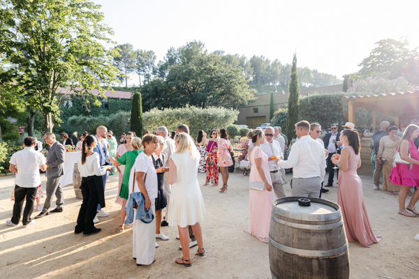 Invités profitant du vin d'honneur dans la cour du Domaine Bunan lors d'un mariage ensoleillé à La Cadière d'Azur.